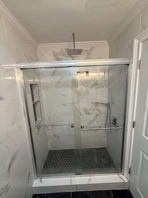 A glass-enclosed shower with a marble wall, a showerhead, and a handrail. - Modern 3BR Jersey City Retreat Near NYC & FIFA (Jersey City)