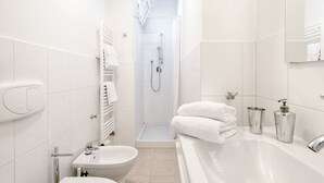 A modern bathroom with a bathtub, a shower, a sink, and a toilet.