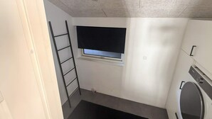 A compact laundry room with a washing machine, a small window, and a black mat.