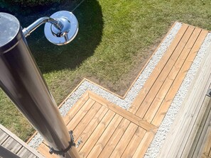 A wooden deck with a metal structure, surrounded by a gravel border and grass. - 5 Star Holiday Home in Frederikshavn (Frederikshavn)