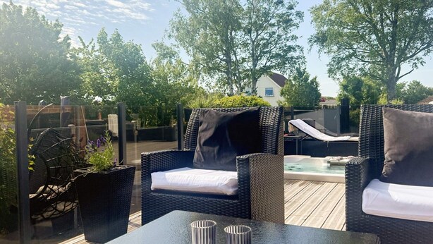 An outdoor patio with wicker furniture, a table, and a hot tub.