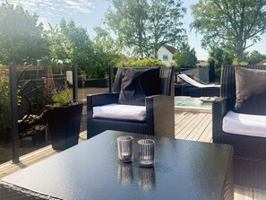 An outdoor patio with wicker furniture, a table, and a hot tub. - 5 Star Holiday Home in Frederikshavn (Frederikshavn)