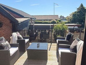 An outdoor patio with wicker furniture, a table, and a view of the surrounding buildings. - 5 Star Holiday Home in Frederikshavn (Frederikshavn)