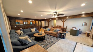 A spacious living room with a sectional sofa, a coffee table, and a dining area with wooden furniture.