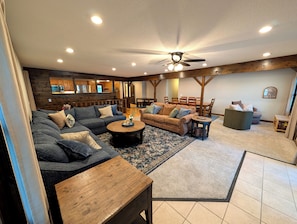 A spacious living room with a sectional sofa, a coffee table, and a dining area with wooden furniture.