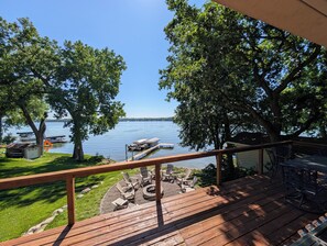 Une terrasse avec des sièges extérieurs donnant sur un lac, des bateaux et des arbres.