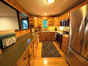 A kitchen with wooden cabinets, stainless steel appliances, and a window.