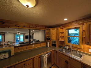 A kitchen with wooden cabinets, a stainless steel sink, and a view of the outdoors.