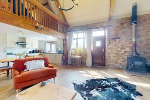 A rustic interior with a wooden staircase, a stone wall, a fireplace, a sofa, and a dining area. - Jasper, Kiri & Norton - joint booking (Dulverton)