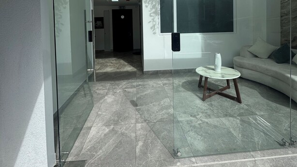 Un intérieur moderne avec un mur en verre, un canapé, une table basse et une porte donnant sur une autre pièce.