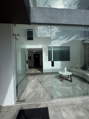 A modern interior with a glass wall, a sofa, a coffee table, and a door leading to another room. - Furnished apartment disconnection with the world Airbnb, La Paz (Baños de Agua Santa)