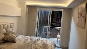 Une chambre avec un lit, une porte-fenêtre coulissante donnant sur un balcon et un tableau accroché au mur.
