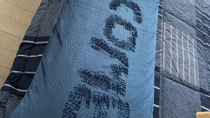 En säng med ett blått täcke och kuddar, ett trägolv och ett fönster med utsikt.