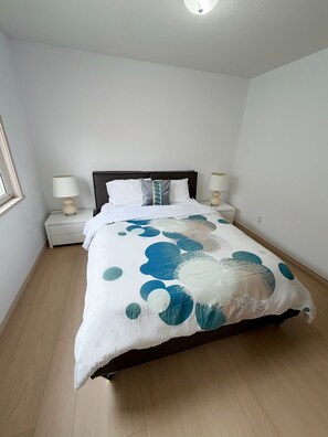 Quarto com cama, duas mesas de cabeceira, janela e luminária no teto.