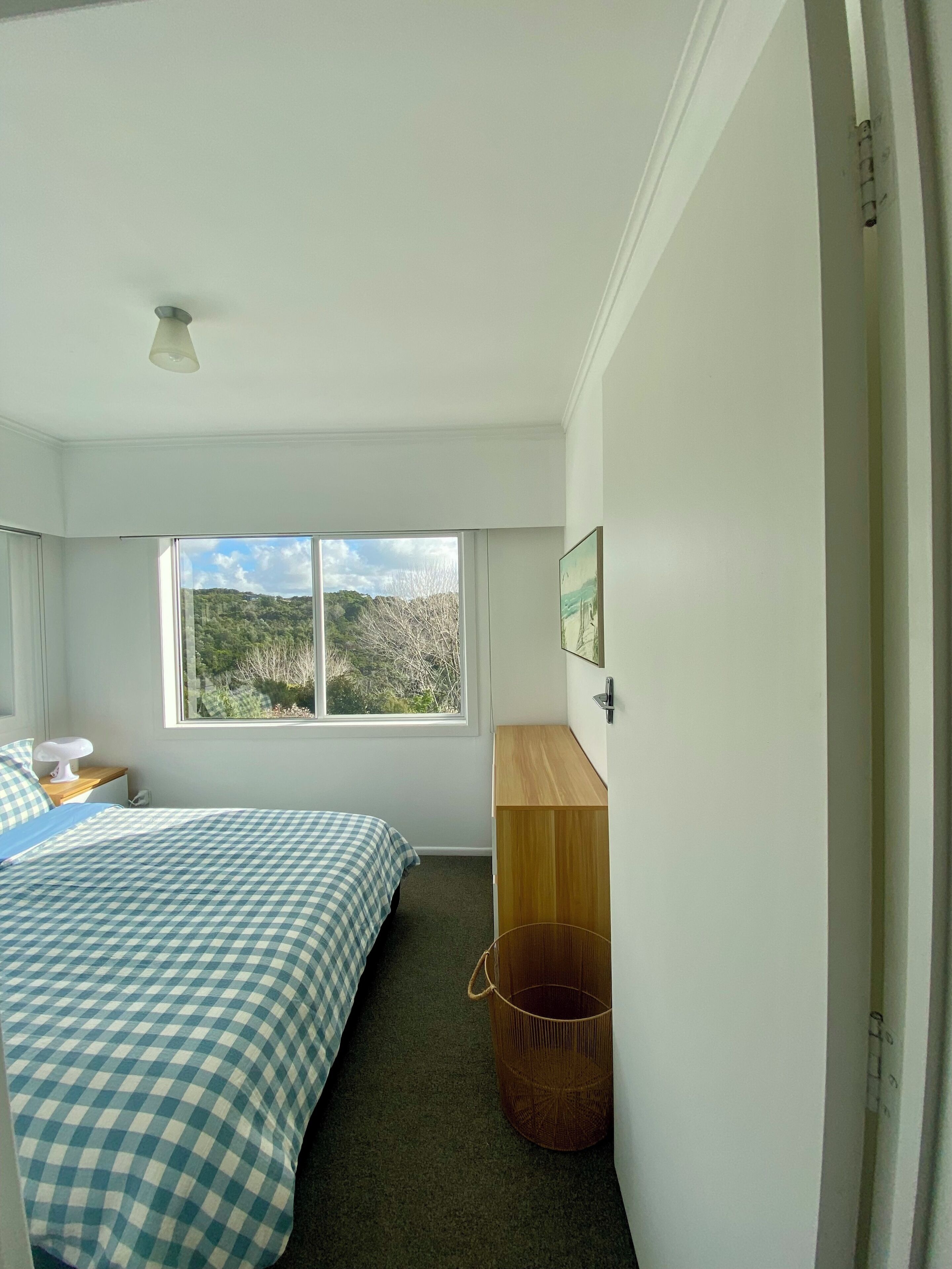 Un dormitorio con cama, un escritorio de madera, una ventana con vistas y un ventilador de techo.