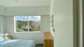 Un dormitorio con cama, un escritorio de madera, una ventana con vistas y un ventilador de techo.