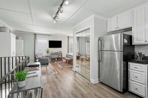Eine moderne Küche mit einem Edelstahlkühlschrank, weißen Schränken und einem Essbereich mit einem Holztisch und einer Bank.