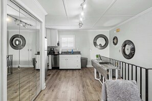 Eine moderne Küche mit weißen Schränken, einer Holz Arbeitsplatte und einem Essbereich mit einer Bank und Geländer.