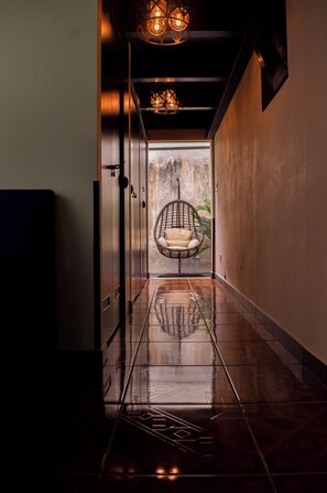 A hallway with a hanging chair, a view through a door, and a tiled floor. - Lolos Place (Antigua Guatemala)