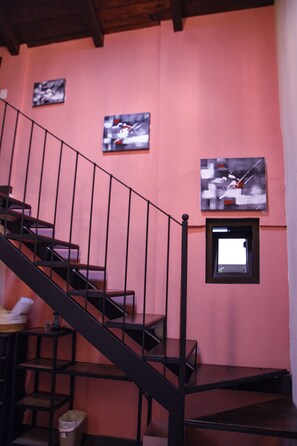 Una escalera con barandilla metálica que conduce a una plataforma. Encima de la plataforma, hay dos obras de arte enmarcadas en la pared.