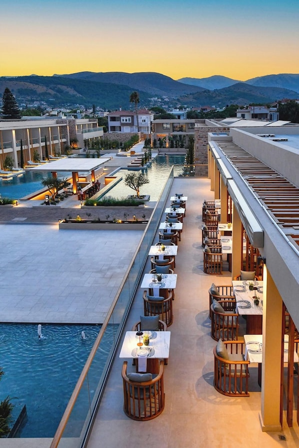 Un área de piscina en la azotea con mobiliario exterior y vistas al paisaje circundante.