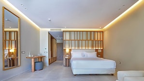 Ett modernt hotellrum med en stor säng, sängbord, en spegel och en sittgrupp.