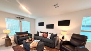 Un salon avec deux canapés, une table basse, un tapis et un fauteuil en cuir.