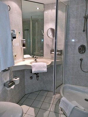 Ein modernes Badezimmer mit einer begehbaren Glasdusche, einem Waschbecken mit Spiegel und einer Toilette.