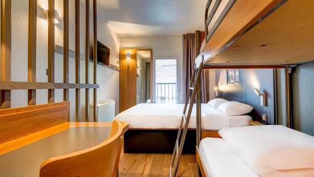 A compact, modern room with two beds, a wooden desk, and a small table. - Hotel Premia Re Classe Roissy Saint Witz (Saint-Witz)