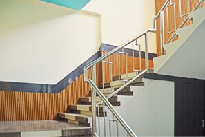 Eine Treppe mit Metallgeländern, Holzvertäfelung an den Wänden und einem Schachbrettfußboden.