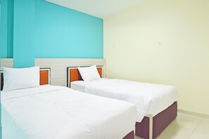 A hotel room with two single beds, a teal accent wall, and a plain beige wall. - Collection O Balikpapan Near Balikpapan Super Bloc (Balikpapan)