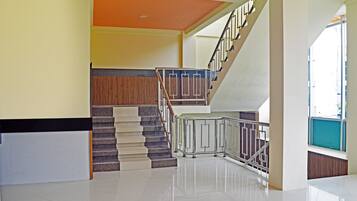 Un interior moderno con una escalera, un mostrador de recepción y un techo luminoso.