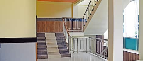 Un interior moderno con una escalera, un mostrador de recepción y un techo luminoso.