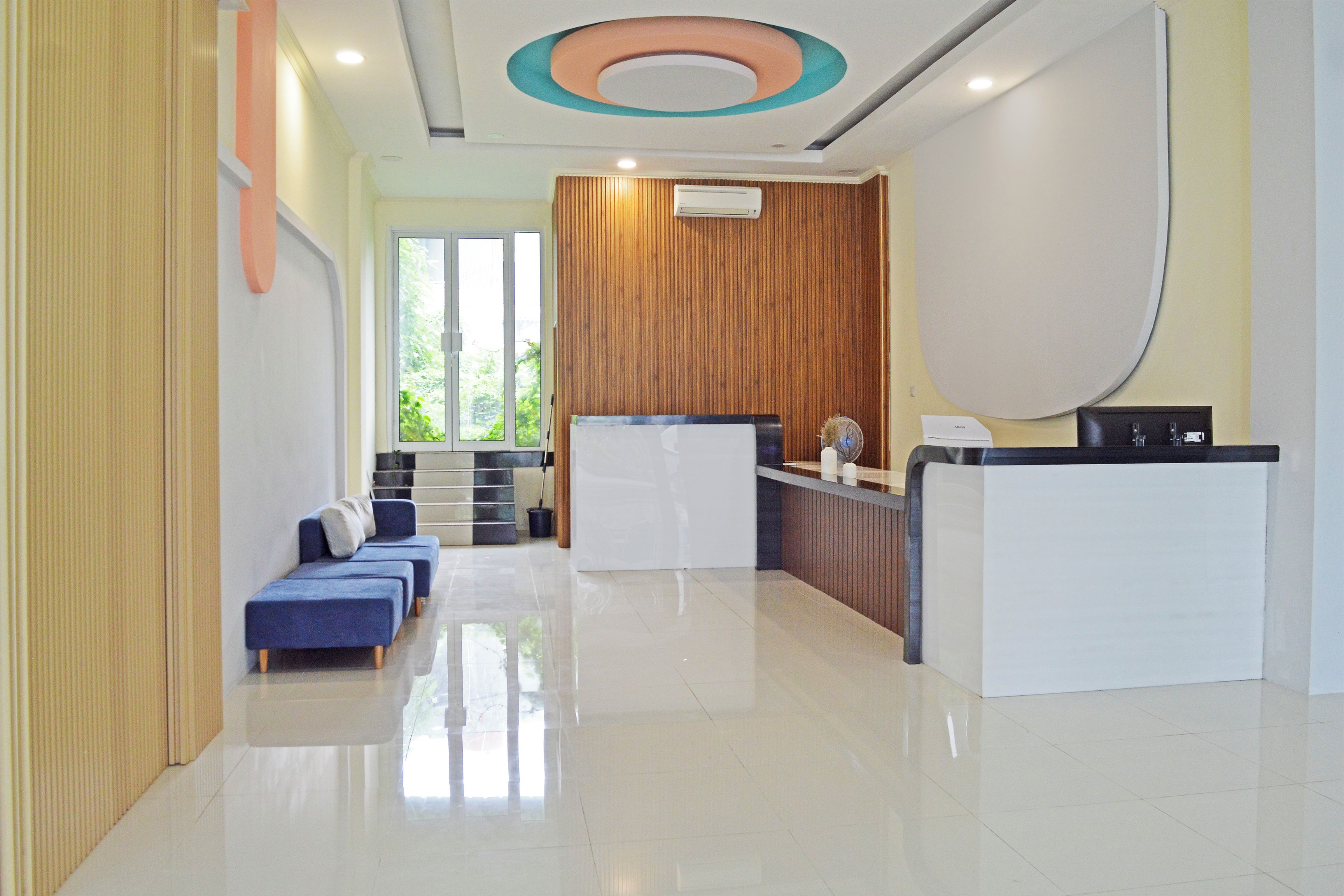 A modern reception area with a reception desk, seating area, and a staircase leading to an upper level.