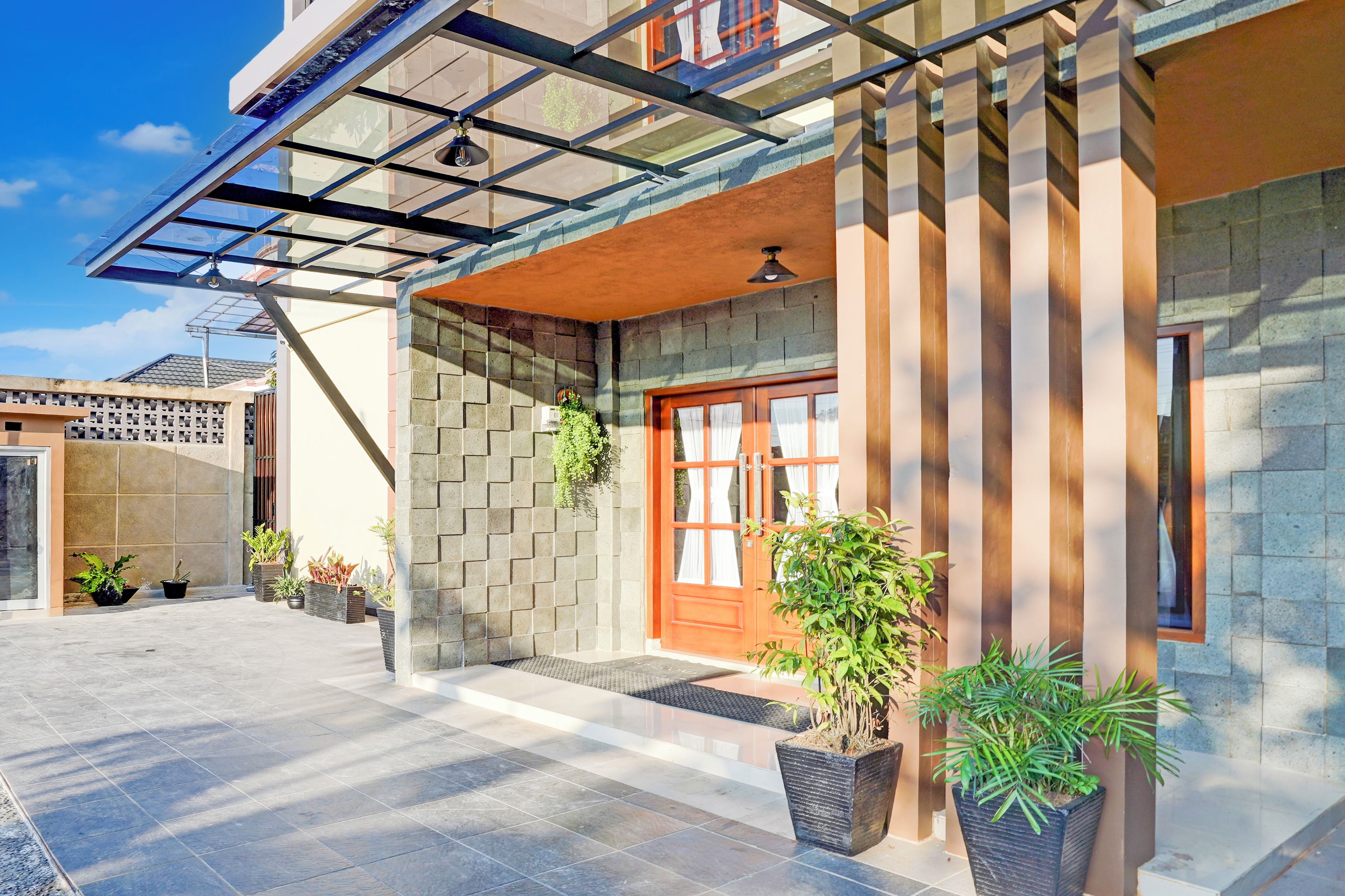 A modern building with a glass entrance, a wooden door, and potted plants.