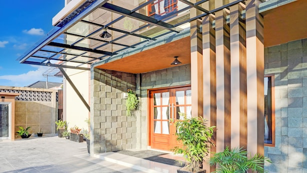 A modern building with a glass entrance, a wooden door, and potted plants. - Collection O Padang C Center Near Transmart Padang (Padang)