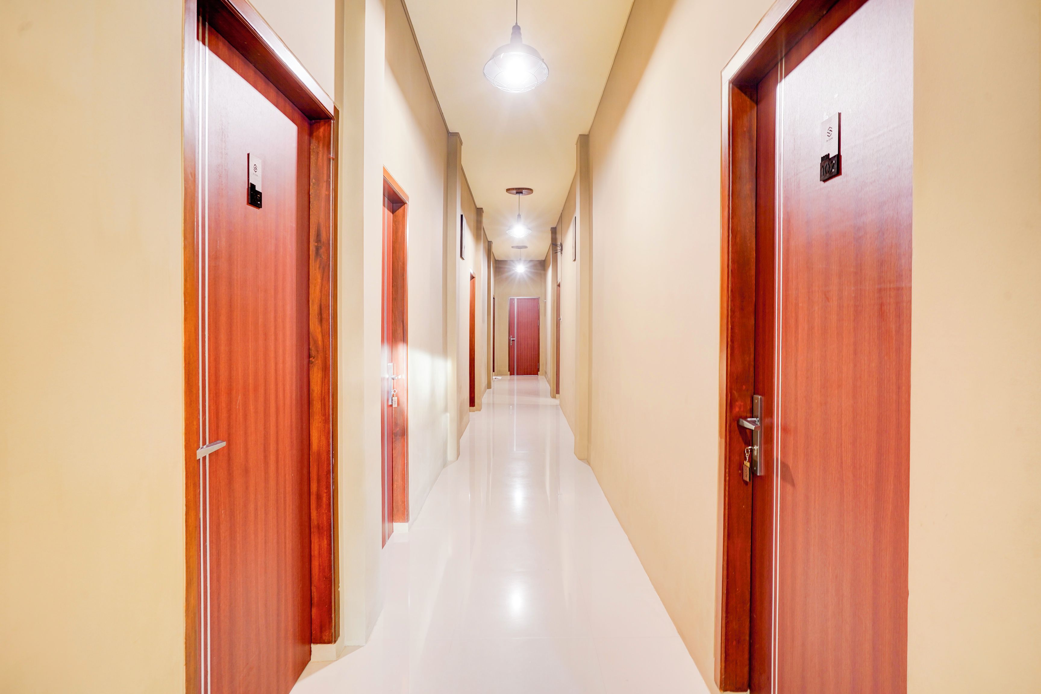 A corridor with wooden doors and a white floor.
