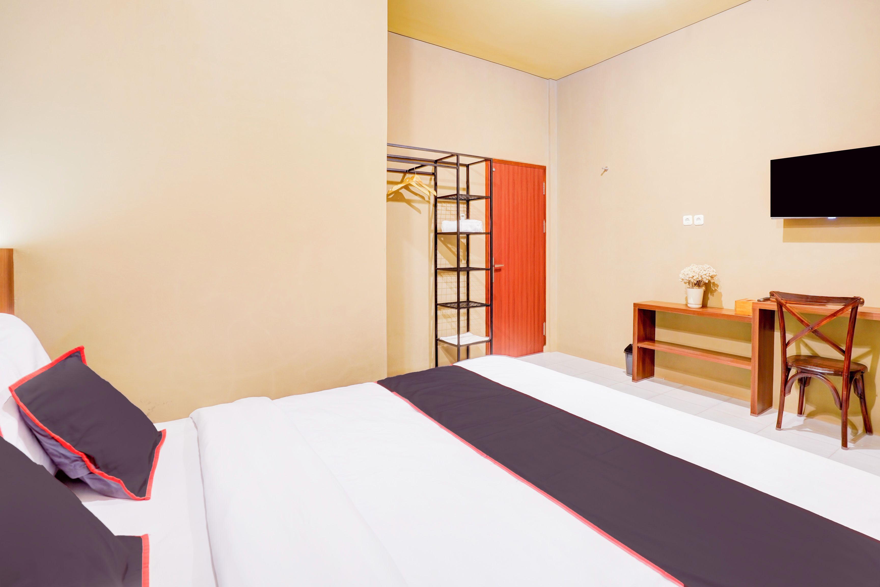 A hotel room with a bed, a desk, a chair, a TV, and a wardrobe.