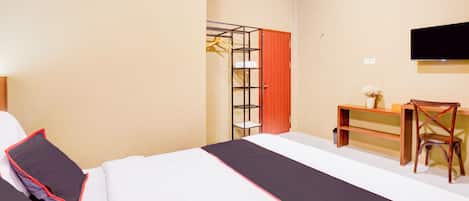 A hotel room with a bed, a desk, a chair, a TV, and a wardrobe.