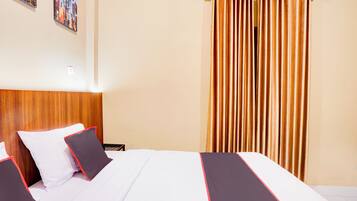 A hotel room with a wooden headboard, a bed with white bedding and red trim, a nightstand, and a curtain.