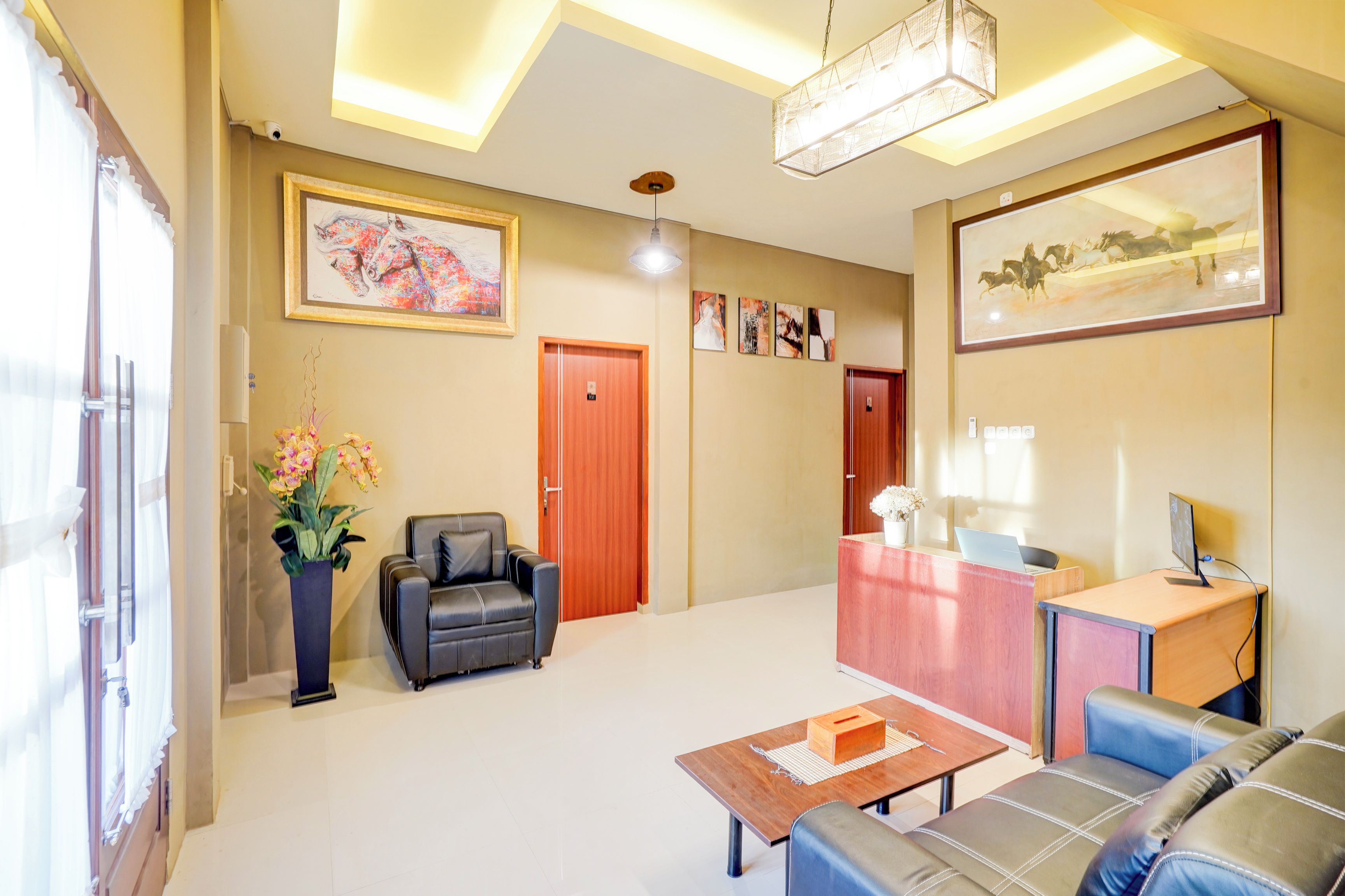 A modern hotel lobby with a reception desk, seating area, and artwork on the walls.