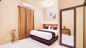 A hotel room with a bed, a mirror, a small table with a vase, and a window with curtains. - Collection O Padang C Center Near Transmart Padang (Padang)