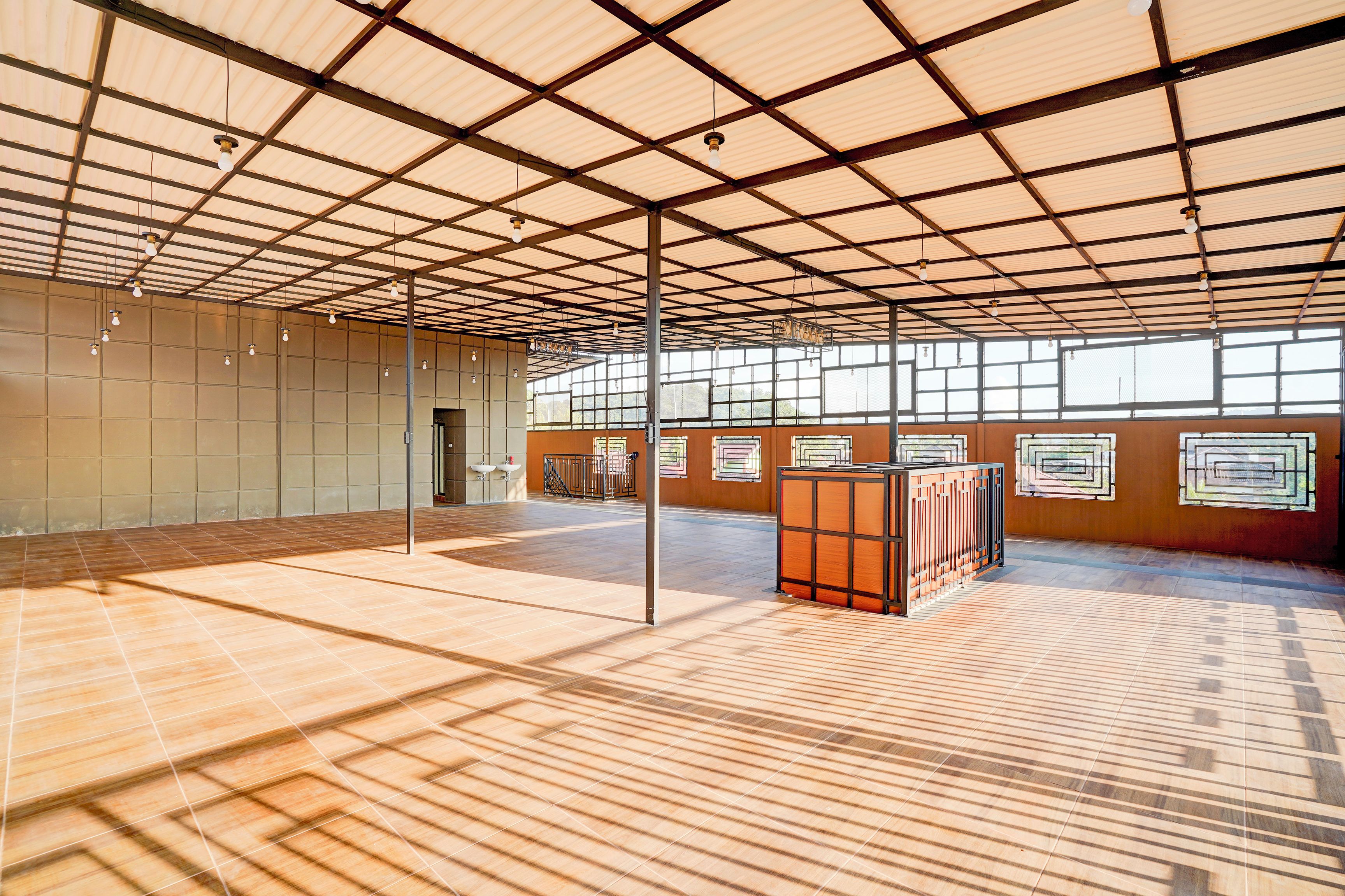 A spacious indoor area with a high ceiling, large windows, and a tiled floor.
