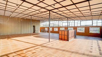 A spacious indoor area with a high ceiling, large windows, and a tiled floor.