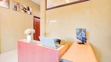 Un mostrador de recepción con una computadora portátil, un florero y un monitor que muestra imágenes de seguridad.