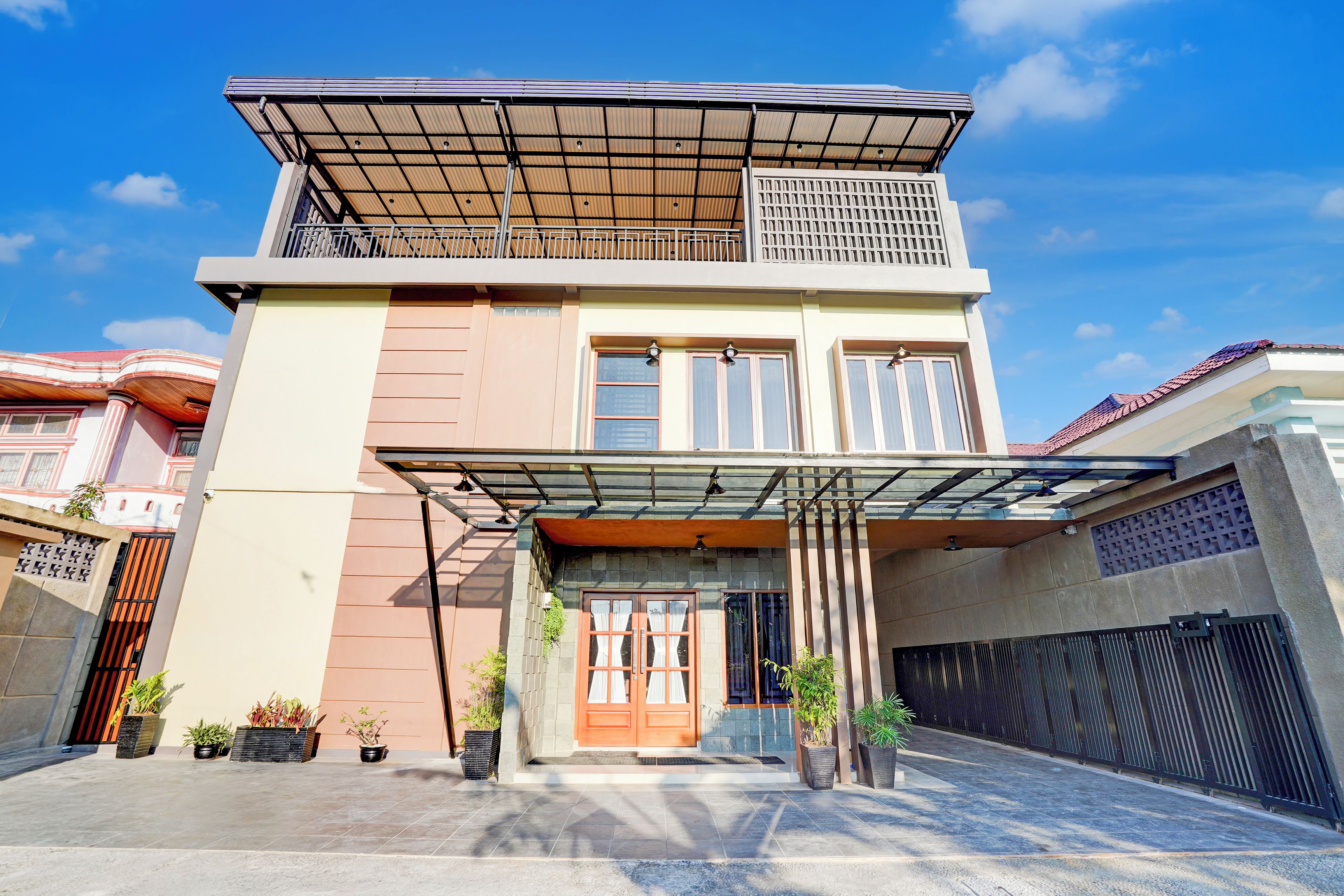 A two-story house with a covered entrance, potted plants, and a gated driveway.