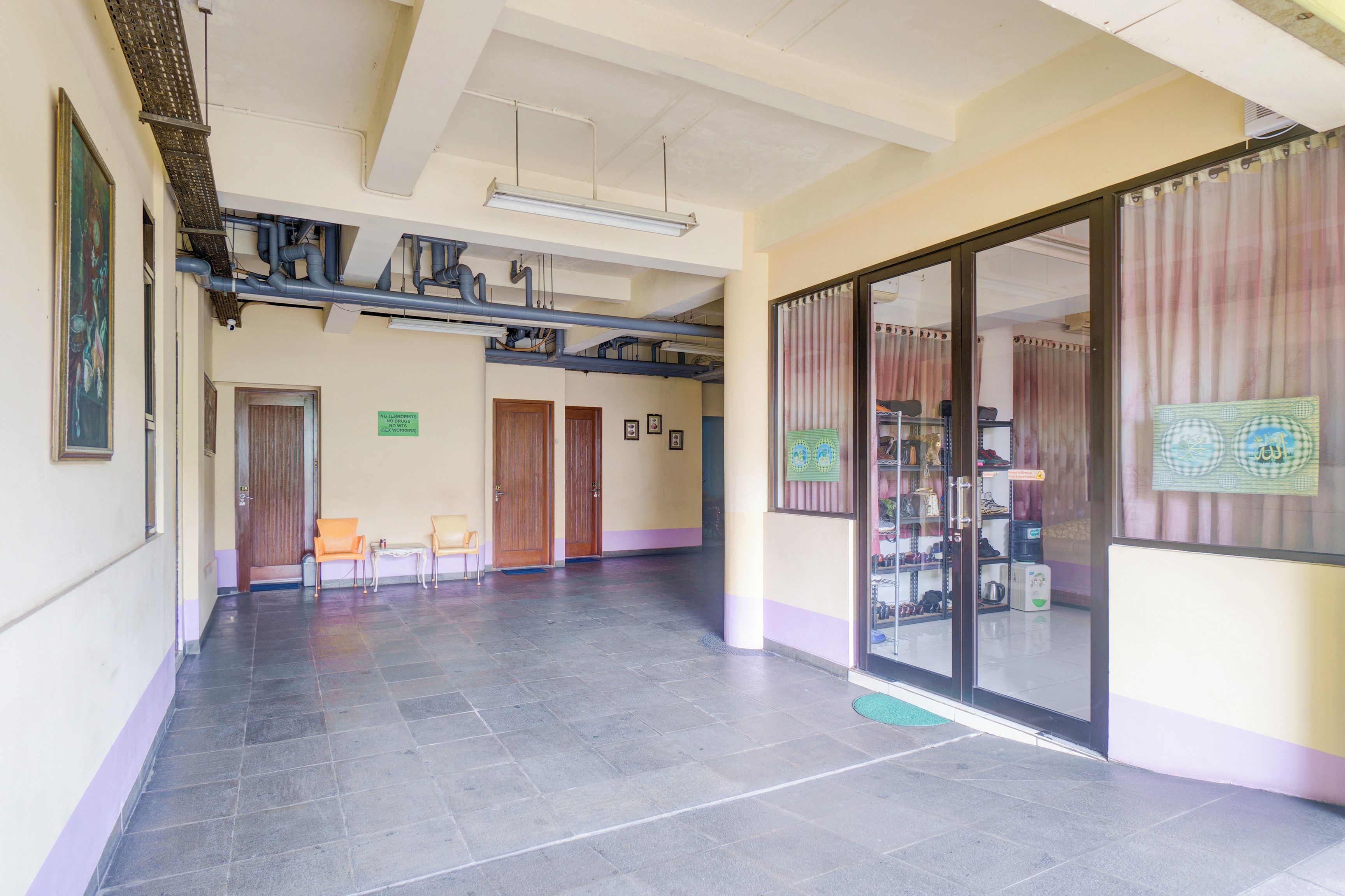 A spacious hallway with a tiled floor, wooden doors, and a glass door leading to a room with shoes displayed.