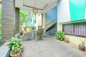 Un patio con mesa y sillas, plantas en macetas y una escalera.