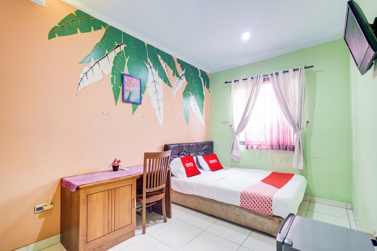 Un dormitorio con cama, escritorio, silla y un mural en la pared.