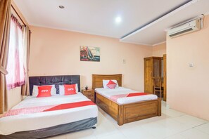 Habitación de hotel con dos camas, cabecera de madera, mesita de noche y un cuadro en la pared.